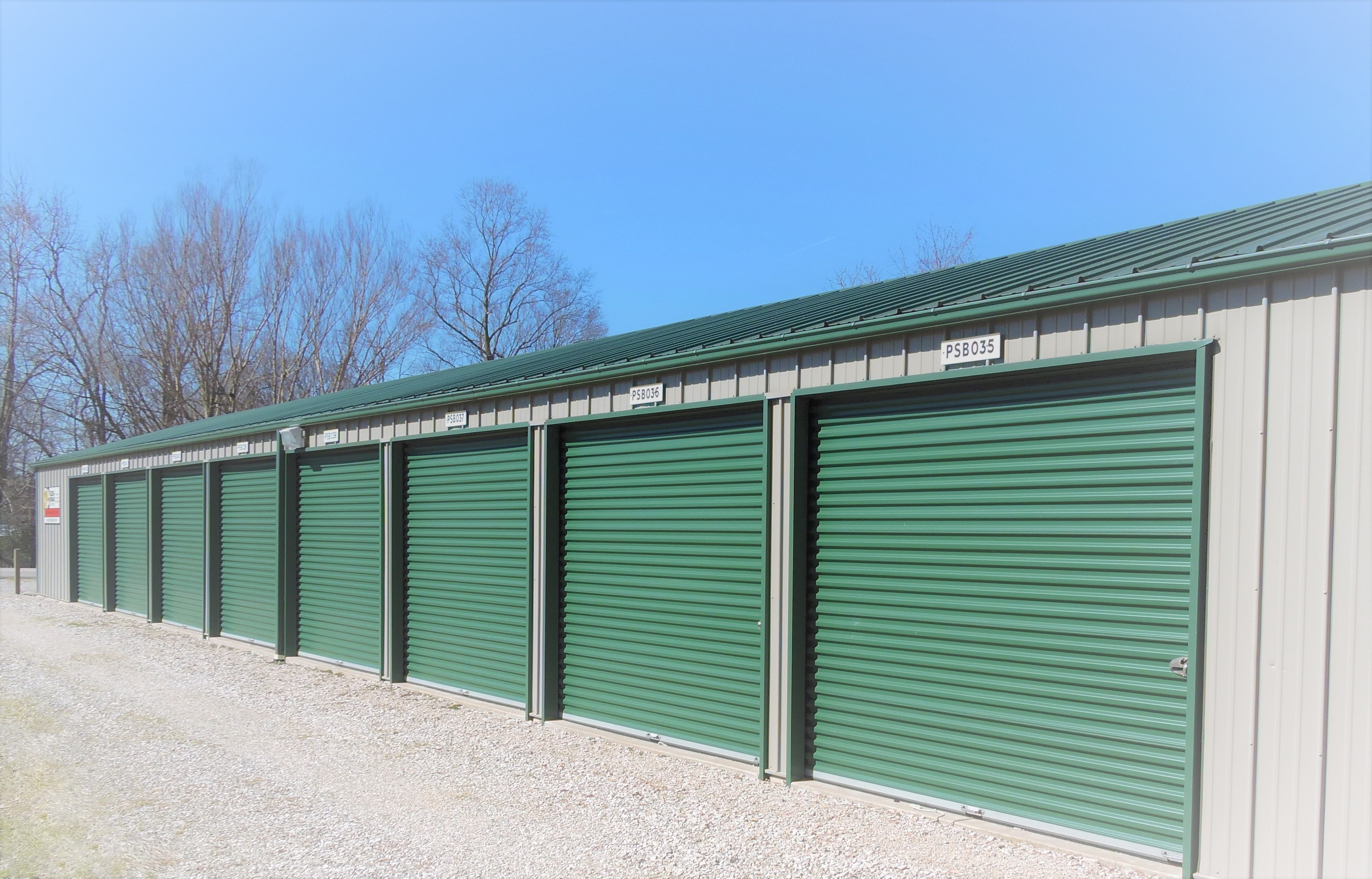 Green roll-up doors at Birdseye Access Storage Now, featuring drive-up units, 24/7 access, and online bill pay options."